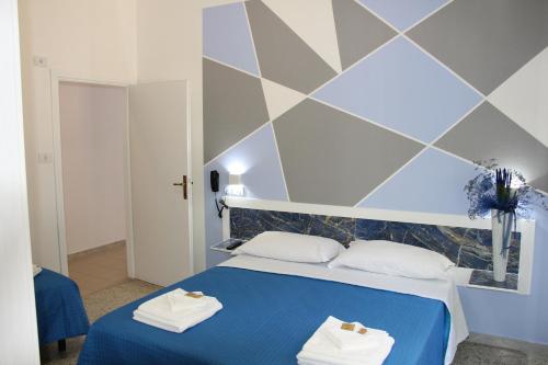 ein Schlafzimmer mit einem blauen Bett, auf dem Handtücher liegen in der Unterkunft Martina's Hotel in Rimini