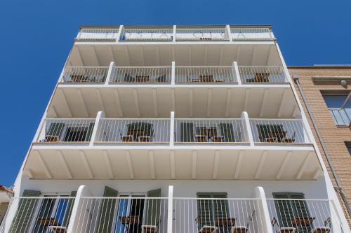 an apartment building with white balconies and chairs at Hostal Olga in Sant Antoni de Calonge