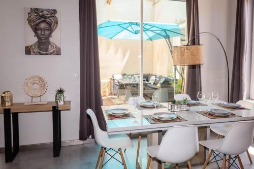 une table à manger avec des chaises blanches et un parasol bleu dans l'établissement Duplex moderne centre Narbonne, à Narbonne