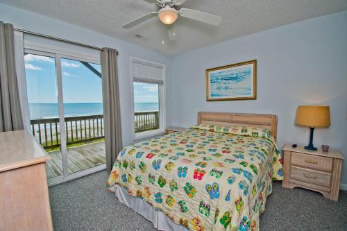 a bedroom with a bed and a balcony with the ocean at Great Expectations West in Emerald Isle