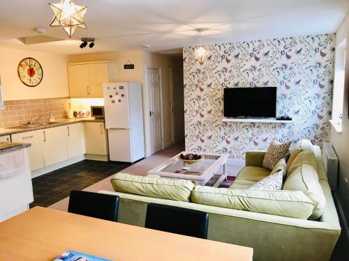 a living room with a couch and a kitchen at The Coach House in Par