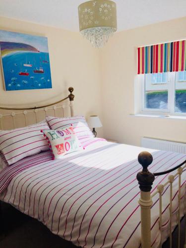 a bedroom with a bed with striped sheets and a chandelier at The Coach House in Par