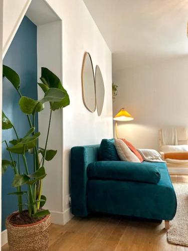 - un canapé bleu dans un salon avec une plante dans l'établissement La perle Bleue - appartement cosy à La Défense, à Puteaux