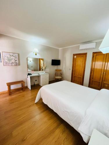 a bedroom with a large white bed and a desk at Hotel Salvador in Bailén