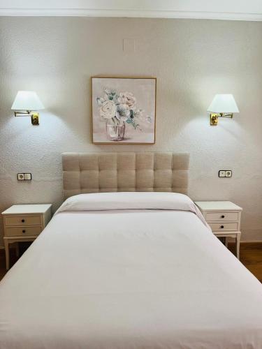 a bedroom with a white bed and two lamps at Hotel Salvador in Bailén