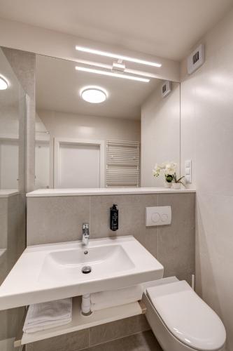 a white bathroom with a sink and a toilet at King Apartamenty Galaxy in Szczecin