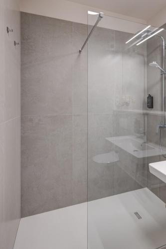a glass shower in a bathroom with a sink at King Apartamenty Galaxy in Szczecin