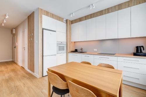 a kitchen with a wooden table and white cabinets at King Apartamenty Galaxy in Szczecin
