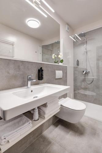a white bathroom with a sink and a toilet at King Apartamenty Galaxy in Szczecin