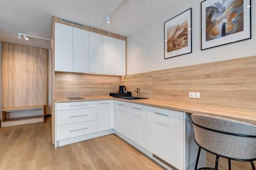 a kitchen with white cabinets and a counter with two stools at King Apartamenty Galaxy in Szczecin