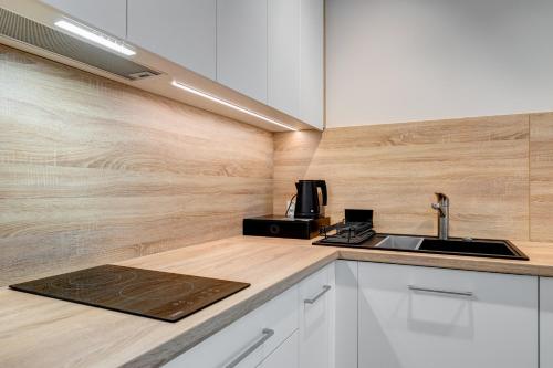 a kitchen with white cabinets and a sink at King Apartamenty Galaxy in Szczecin