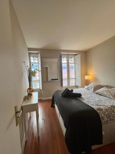 une chambre avec un lit, une table et des fenêtres dans l'établissement Capitole - Centre ville, à Toulouse