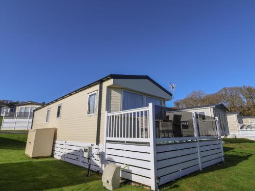 a mobile home with a deck on a lawn at Tri-Star House in Charmouth