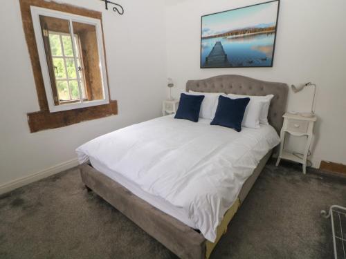 une chambre avec un grand lit avec des oreillers bleus dans l'établissement Whim Cottage, à Hathersage