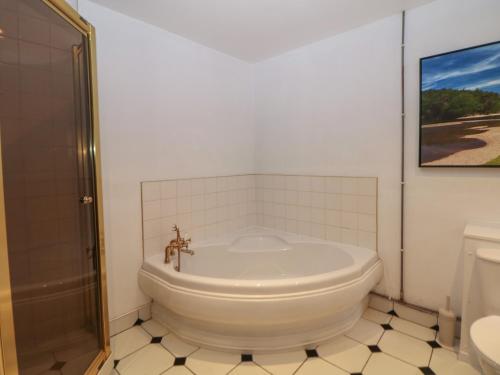 une salle de bain blanche avec une baignoire et une douche dans l'établissement Whim Cottage, à Hathersage