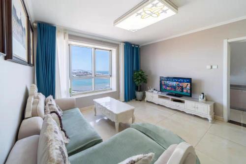 a living room with a couch and a tv at Cloud & Sea Boutique Apartment in Rizhao