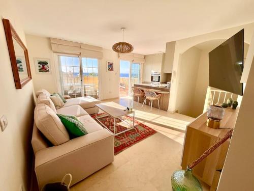 a living room with a white couch and a television at Sea view duplex private jacuzzi, garden, terras and shared pool in Palm-Mar