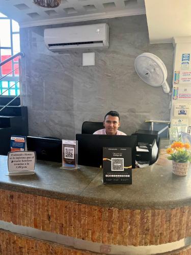 a man sitting at a counter with a laptop at Hotel La Casa N. 3 in Montería