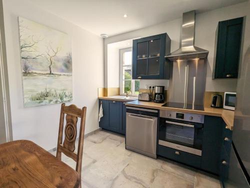 La cuisine est équipée de placards bleus et d'un four avec plaques de cuisson. dans l'établissement Le chant de la rivière en Berry, à Ardentes