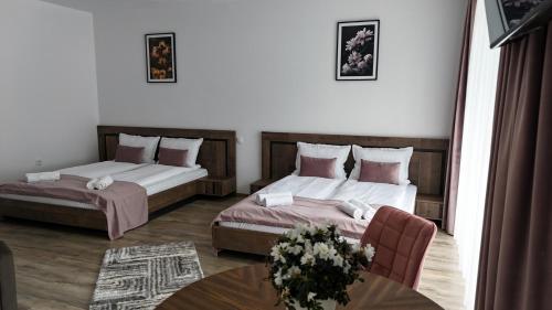 a hotel room with two beds and a table at Pensiunea Royal Panzió in Praid