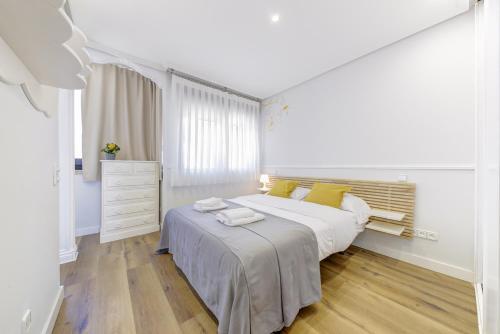 a white bedroom with a large bed with yellow pillows at El Palomar in Madrid