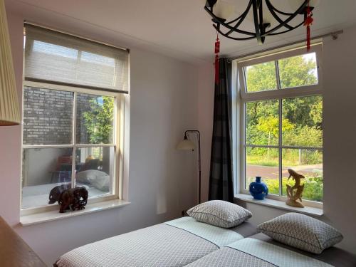 a bedroom with a bed and two windows with a dog statue at Room D no bathroom, geen badkamer in Aalten