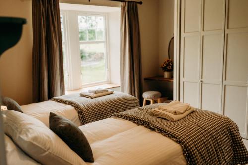 deux lits dans une chambre avec une fenêtre dans l'établissement No1 Burgie Mains Cottage, à Forres