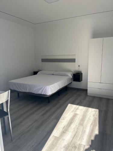 a white bedroom with a bed and a chair at Villa Amir in Fuengirola