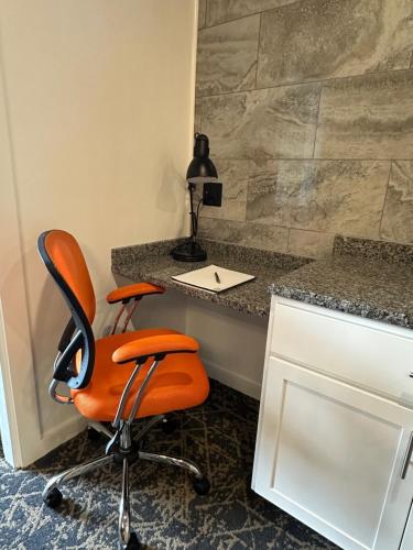 an orange office chair sitting in front of a desk at Stone Park Ellsworth-Bar Harbor in Ellsworth