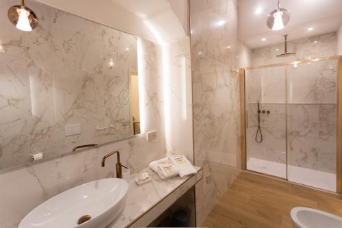 une salle de bain blanche avec un lavabo et une douche dans l'établissement Heraklean Suites Tropea, à Tropea