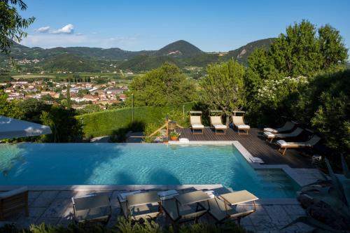 a swimming pool with chairs and a view of mountains at Oasi Dolce Vita in Lozzo Atestino