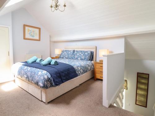 a bedroom with a bed with a blue comforter at Bwthyn y Gwas in Tywyn