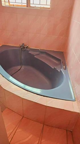 a blue bath tub in a bathroom with a window at Happy Stay Guest House Mafikeng in Mahikeng