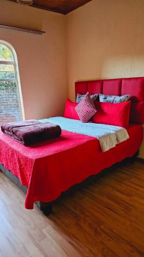a bedroom with a large bed with red sheets and pillows at Happy Stay Guest House Mafikeng in Mahikeng