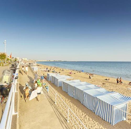 - une plage avec des parasols bleus et blancs et des personnes y séjournant dans l'établissement L'Océan à Vos Pieds Appartement Vue Panoramique La Baule, à La Baule