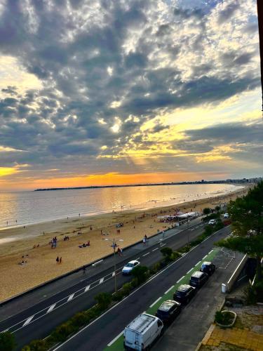 - une vue sur une plage avec des voitures garées sur la route dans l'établissement L'Océan à Vos Pieds Appartement Vue Panoramique La Baule, à La Baule