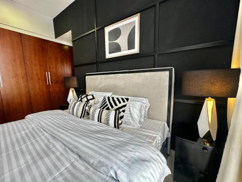1 dormitorio con 1 cama con sábanas y almohadas a rayas en Oreo Home 75inch TV 5mints from Beach & City, en Dar es Salaam