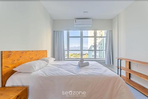 a bedroom with a bed with a large window at Aptos modernos no centro de Floripa - VLR in Florianópolis