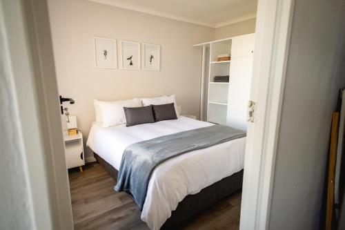 a small bedroom with a bed with white sheets at Ocean Whisper Unit 79 in Hermanus