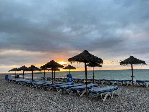 a line of chairs and umbrellas on a beach at Magnífico piso con vistas al mar en Moncofa in Moncófar