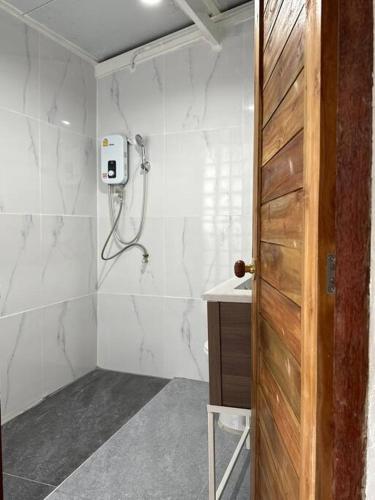 a bathroom with a shower and a wooden door at Megun 10 in Ban Bang Phlat