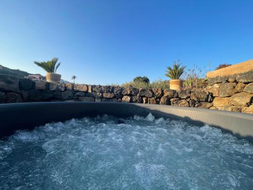a hot tub in a backyard with a stone wall at La Grotta di benikula' in Pantelleria