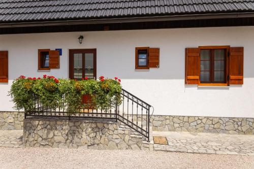 a white house with a balcony with flowers on it at Green lakes house 2 in Plitvička Jezera