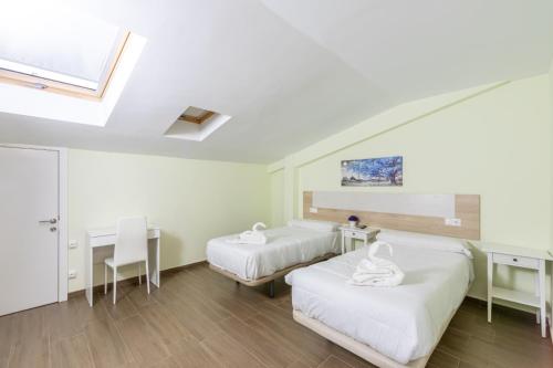 a room with two beds and a desk and a window at Otero & Elma 2 in Alovera