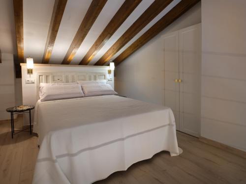 a bedroom with a white bed with a wooden ceiling at V11apartamentos 3 in Archidona