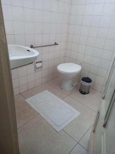 a white bathroom with a toilet and a sink at Hotel Central in Araçatuba