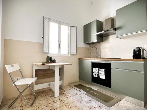 une cuisine avec des placards verts, une table et une chaise dans l'établissement Lucky Corner - Elegant Stay, à Tarente