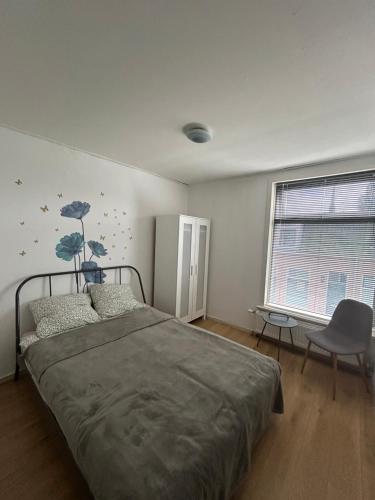 a bedroom with a bed and a chair and a window at Stay and Sleep in Leeuwarden