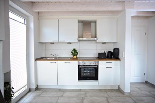 a kitchen with white cabinets and a sink and a stove at Blinkfüer in Nordhorn