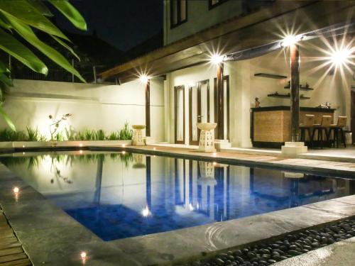 a swimming pool in front of a house at night at Linda Villa Sanur in Sanur